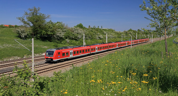 Regiobahn fährt auf Schienen durch eine grüne Landschaft.
